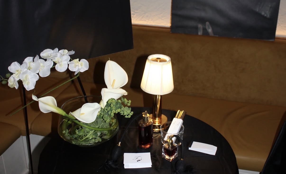 Soirée bottles on a black table with white orchids and a lamp