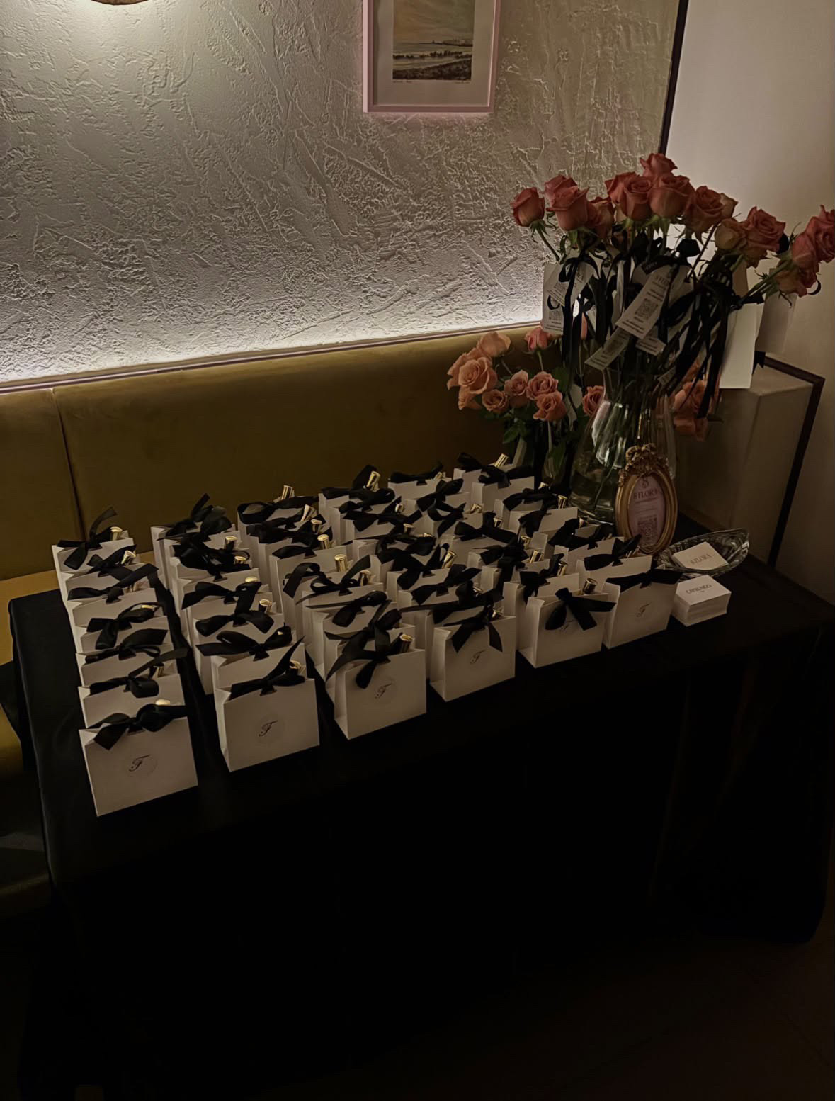 Gift bags tied with black ribbon beside roses